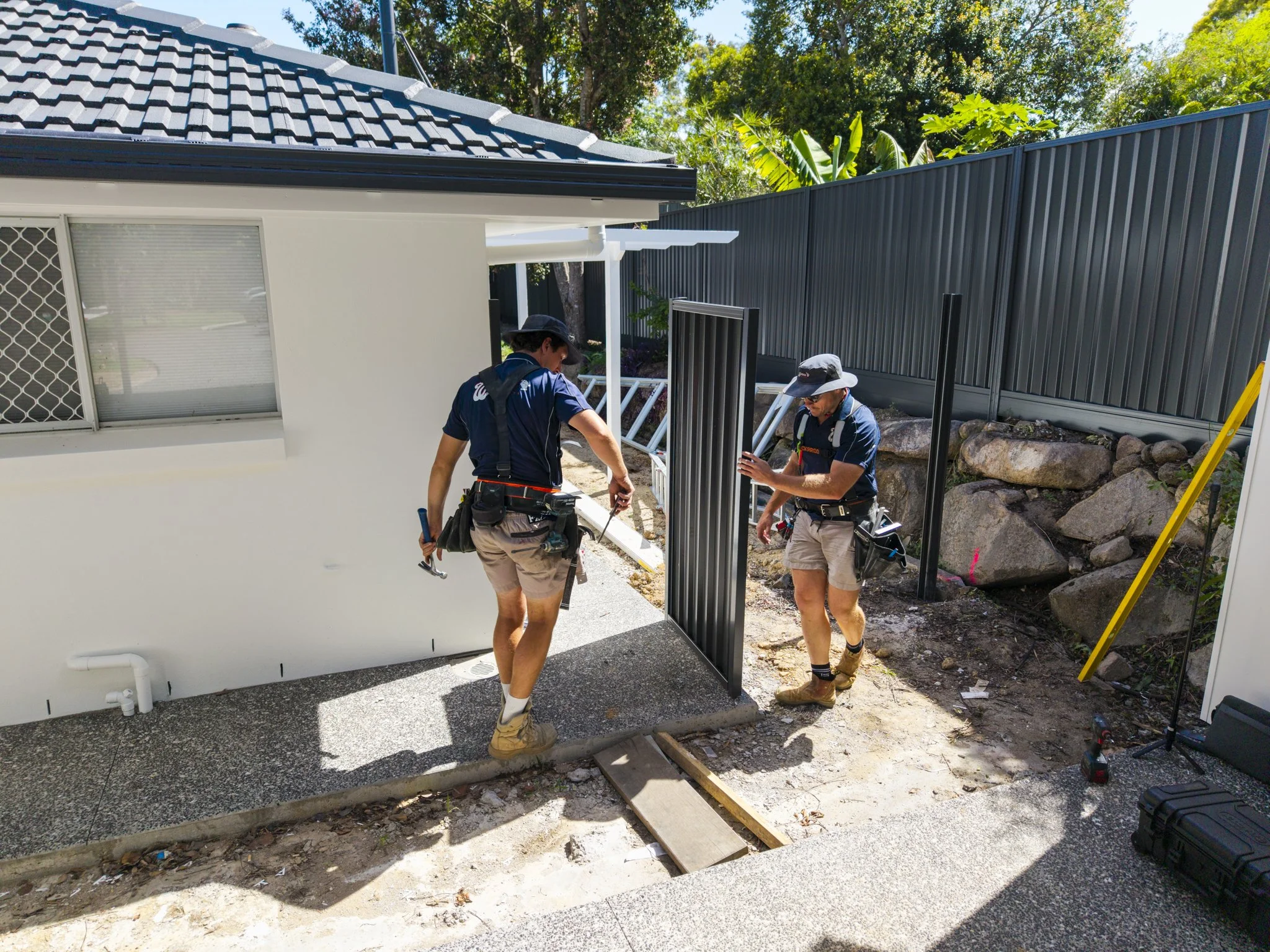 Covered deck with a white railing overlooking trees and a cloudy sky.