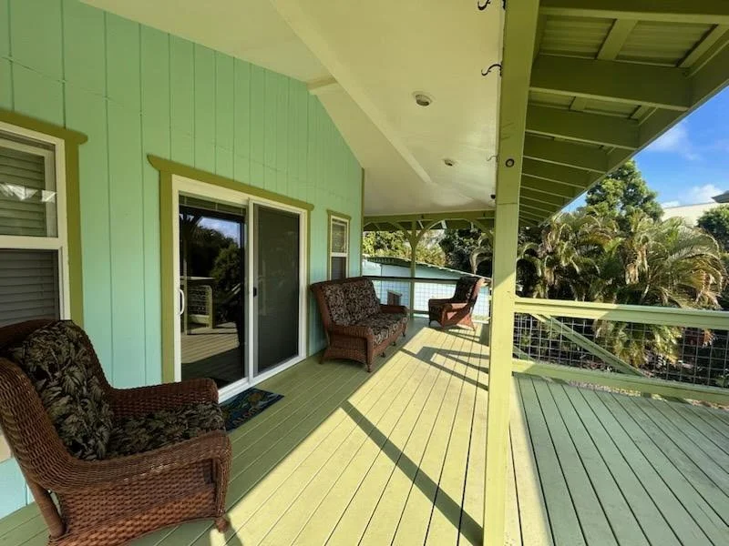Outdoor porch with green railing and wicker chairs