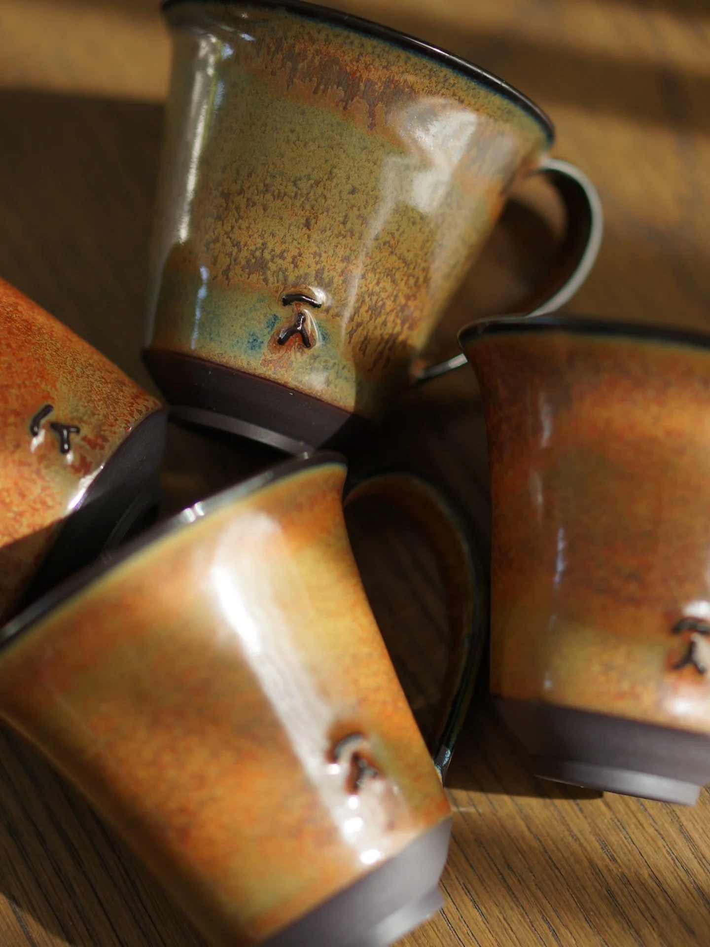 My handled yunomi cups vs. golden hour 🫶🏻🍃. This glaze is quite sensitive to application thickness. The thicker the application, the more rusty orange will come through, and where it&rsquo;s thinner, it will appear more green. You can clearly see 