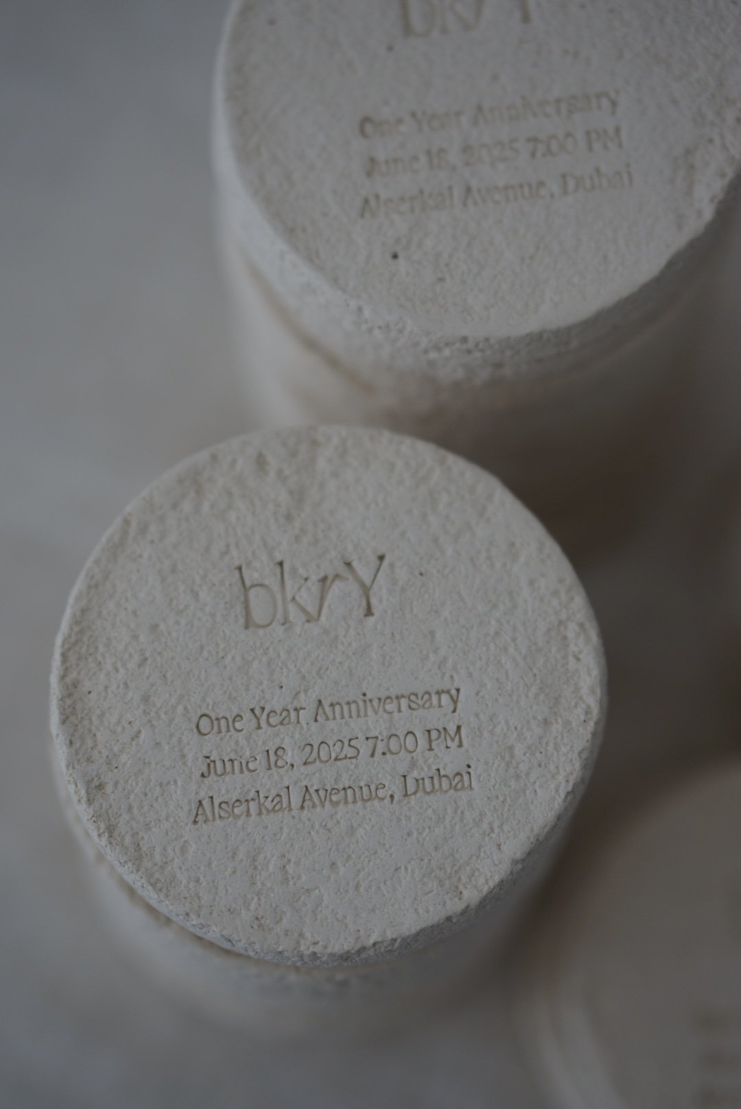Close-up of two white textured tablets engraved with text, one partially visible above the other, celebrating a one-year anniversary at a location in Dubai.