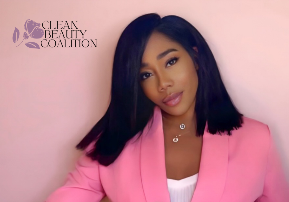 Young woman with black hair wearing a pink blazer and white top, posing against a pink background with 'CLEAN BEAUTY COALITION' logo in the top left corner.