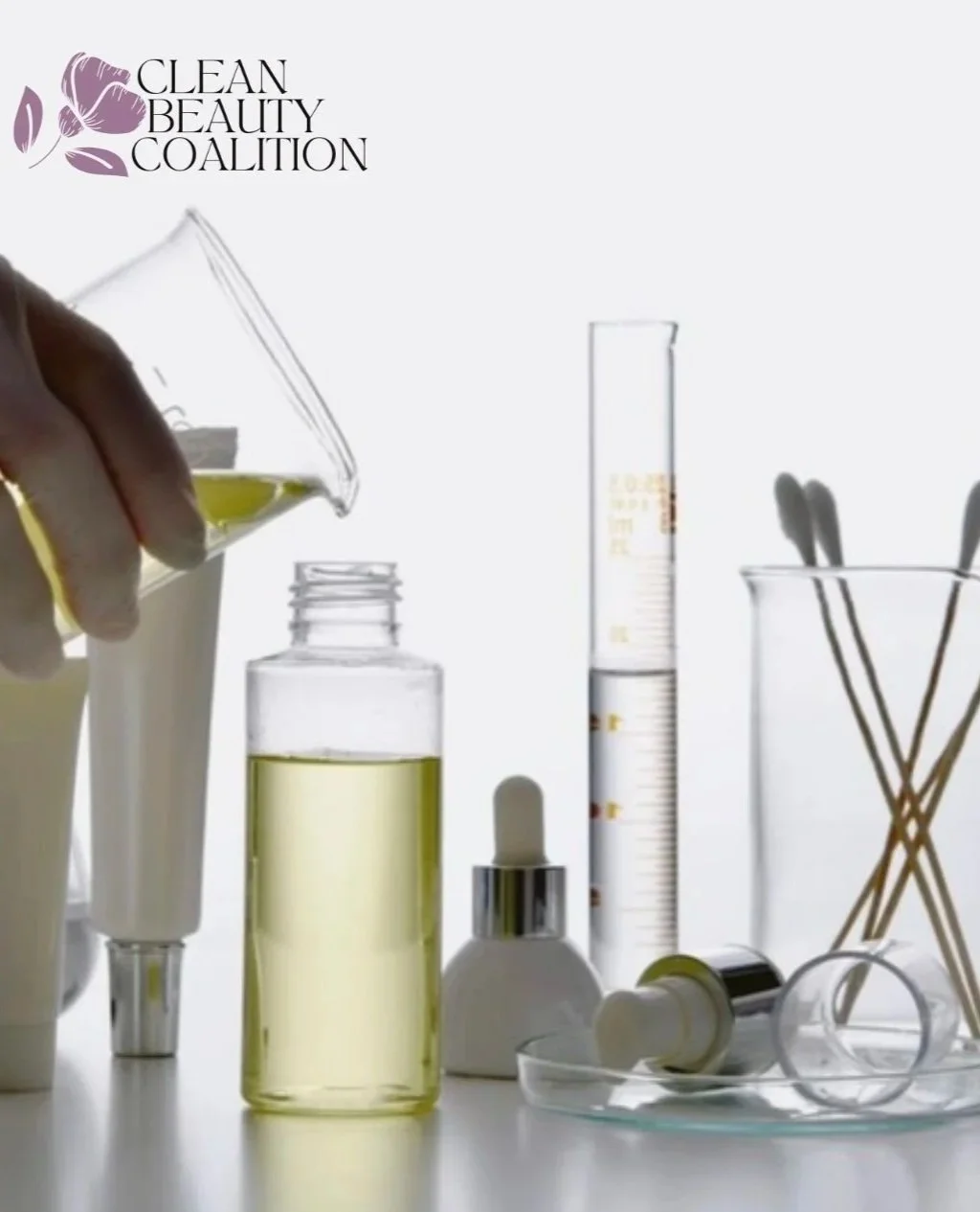 Laboratory scene with various skincare products and tools, including a dropper bottle, test tubes, and cotton swabs, against a white background with the logo of the Clean Beauty Coalition.