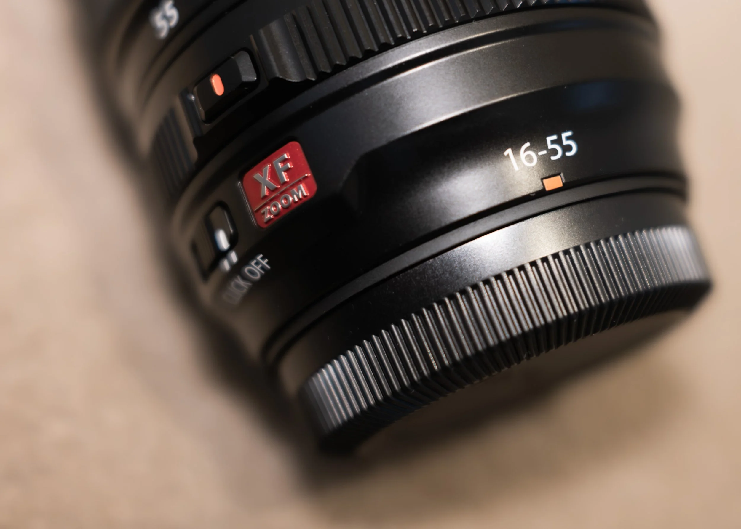 Close-up of a Fujifilm camera lens showing the focus distance from 16 to 55 millimetres, with a red XF zoom label and various adjustment switches.