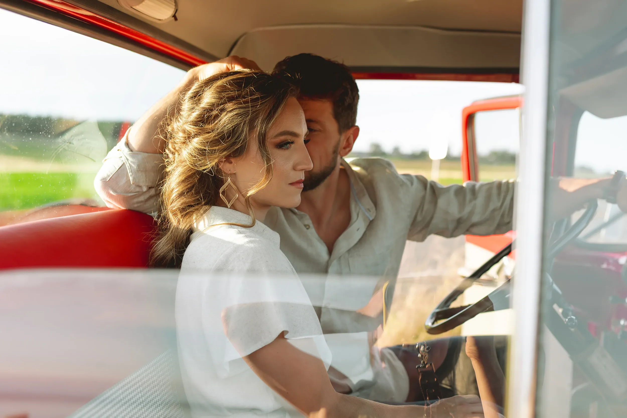 Couple sitting close together inside a vintage truck during a Whidbey Island engagement session at Ebey’s Landing, with warm sunlight and open fields in the background.