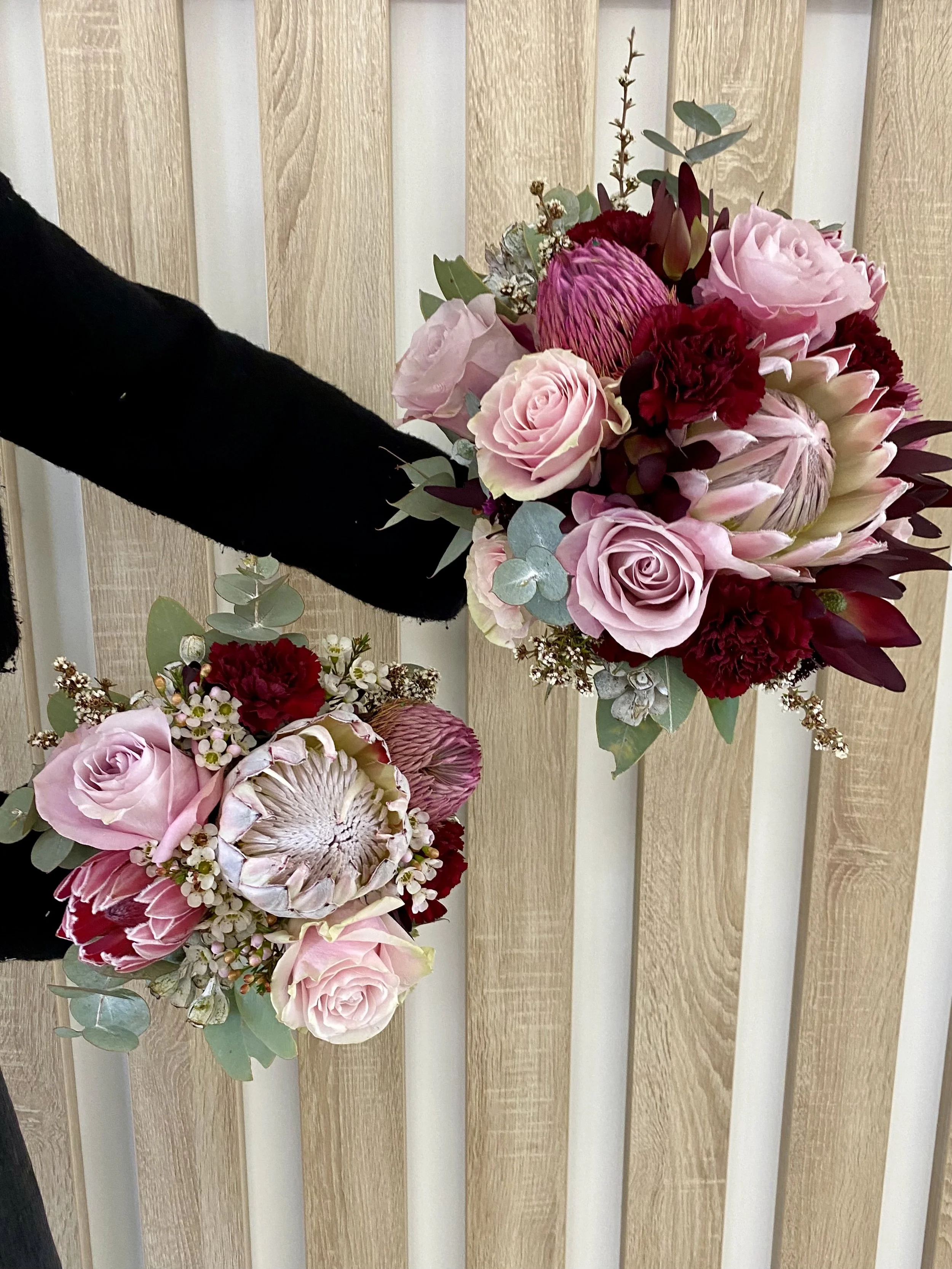 Bride and Bridesmaid bouquets combining native proteas and gum with soft and dusty pink roses, burgundy carnations, wax flower, and mixed eucalyptus. Romantic and earthy wedding florals in soft and rich tones. Designed by Penny Dormer, Perth floral d