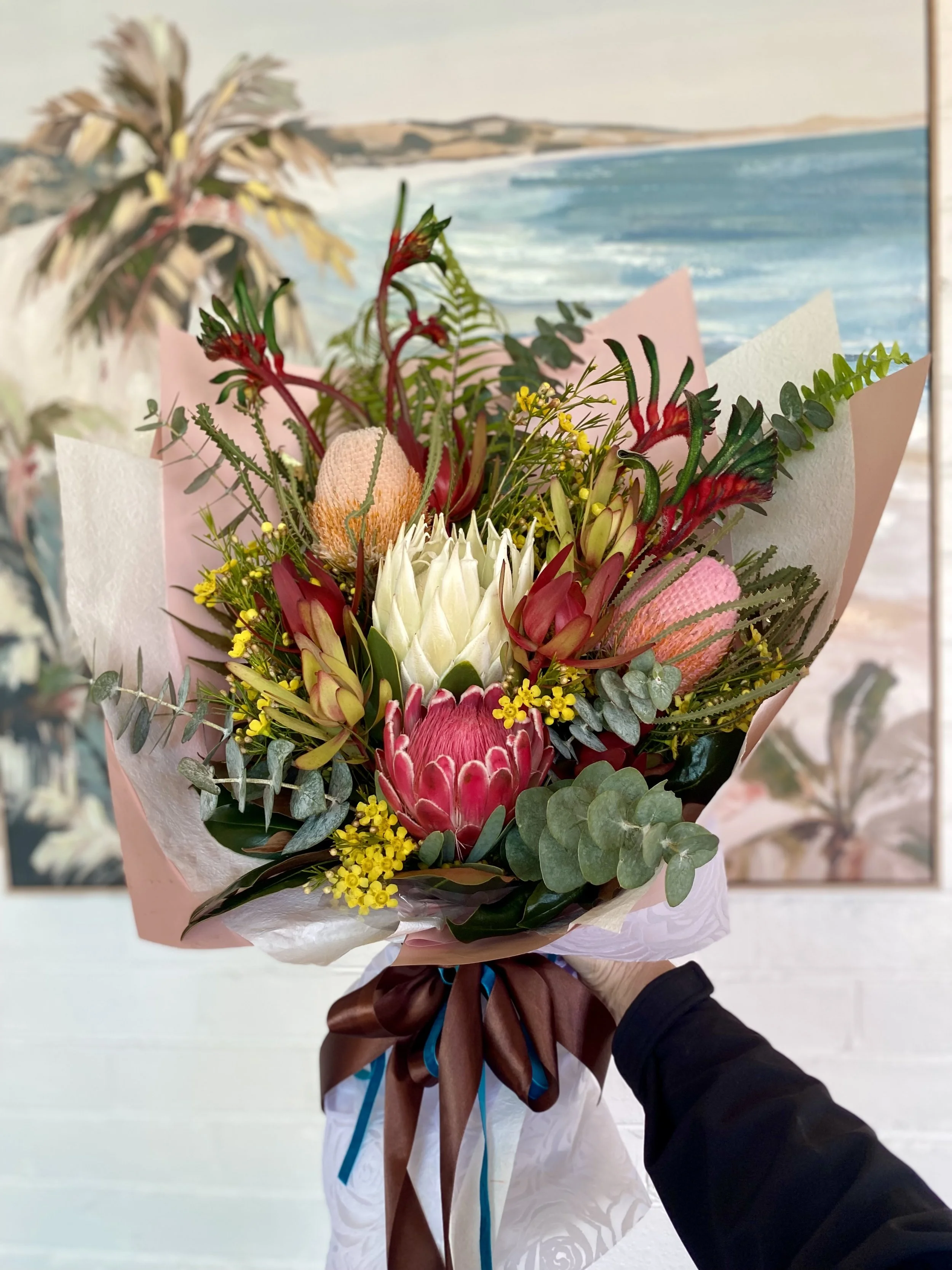 Natives bouquet for a graduation celebration featuring Protea, Banksia, Leucadendron, Kangaroo Paw, Geraldton Wax and Eucalyptus. Beautifully wrapped on premium papers and ribbons. Designed and created by Penny Dormer, Wild Heart Flowers. Perth event