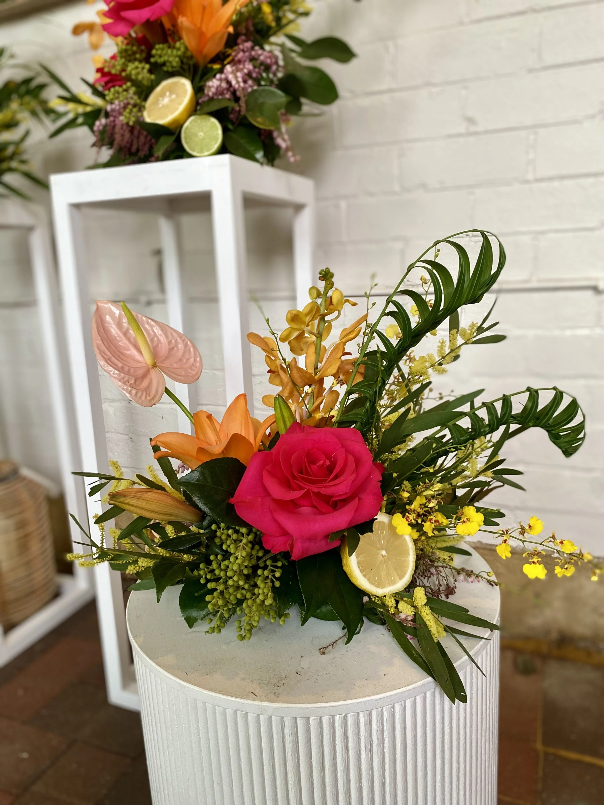 All-round tropical table piece in pink, orange and yellow with blush anthurium and citrus — Penny Dormer, Wild Heart Flowers event florist.
