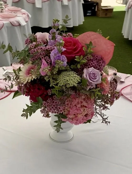 Vibrant guest table arrangement in shades of pink, lavender, and berry. Featuring roses, hydrangea, lisianthus, anthurium, statice, wax flower, queen anne’s lace, and mixed foliage. Designed for a spring garden wedding at Masonmill by Penny Dormer, P