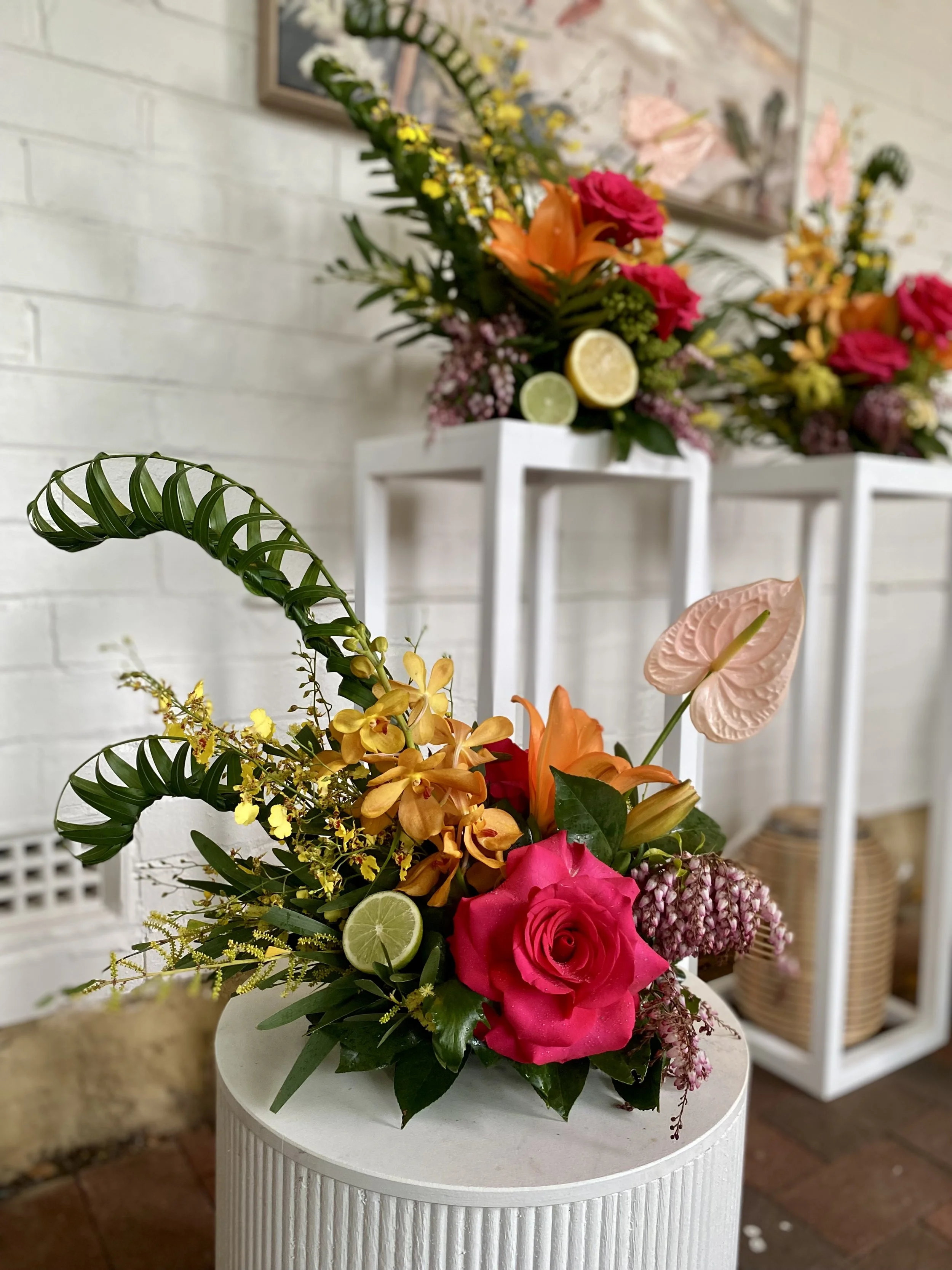 Asymmetrical all-round table arrangement with hot pink rose, orange lilies, gold orchids, blush anthurium and citrus — Penny Dormer, Wild Heart Flowers event florist Perth.