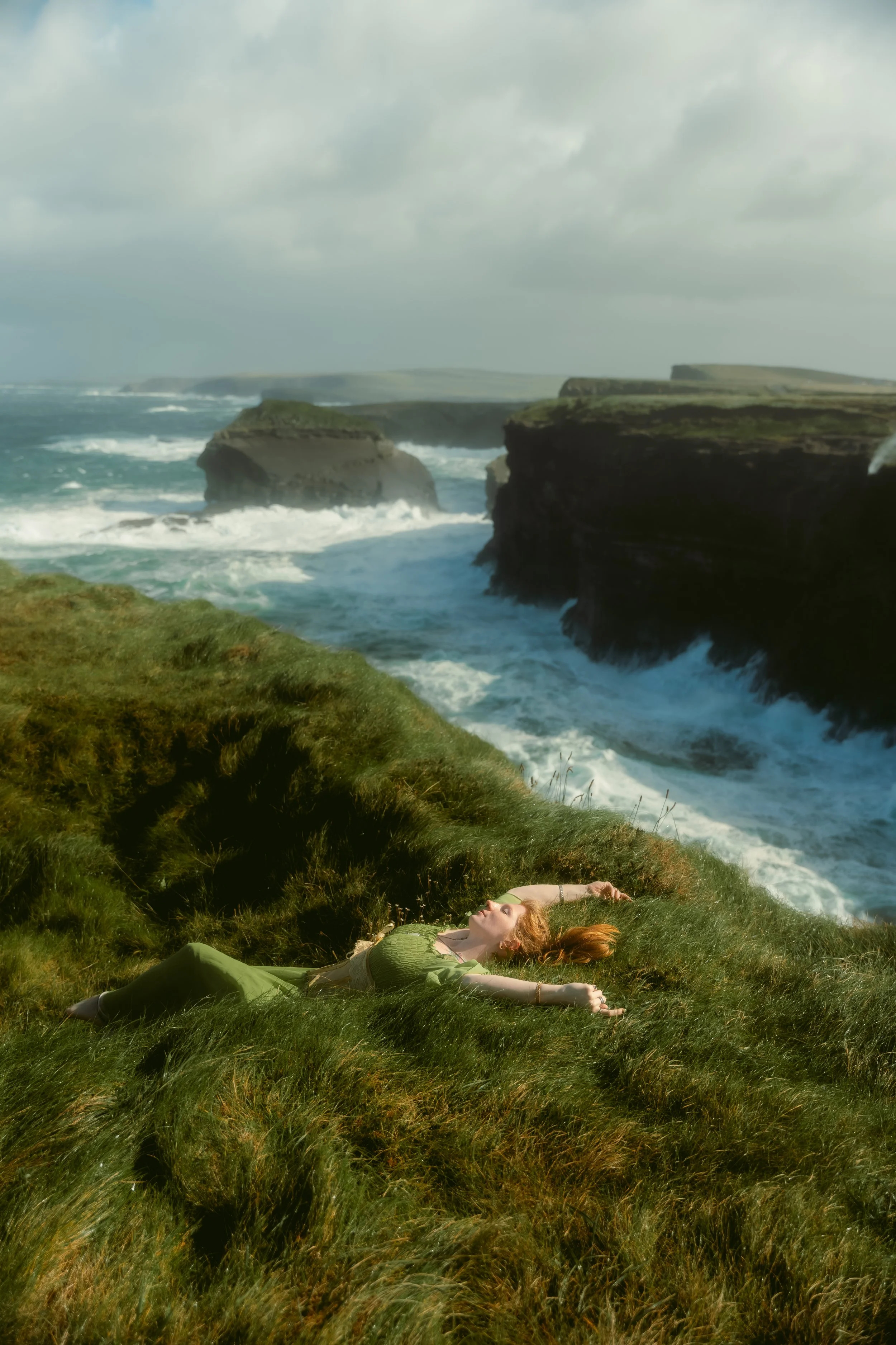Woman laying in the grass next to the Kilkee cliffs.