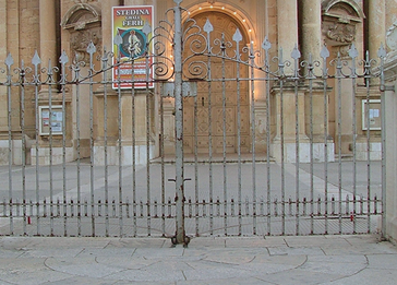 Closure gate in front of an old building with signage and ironwork fence.