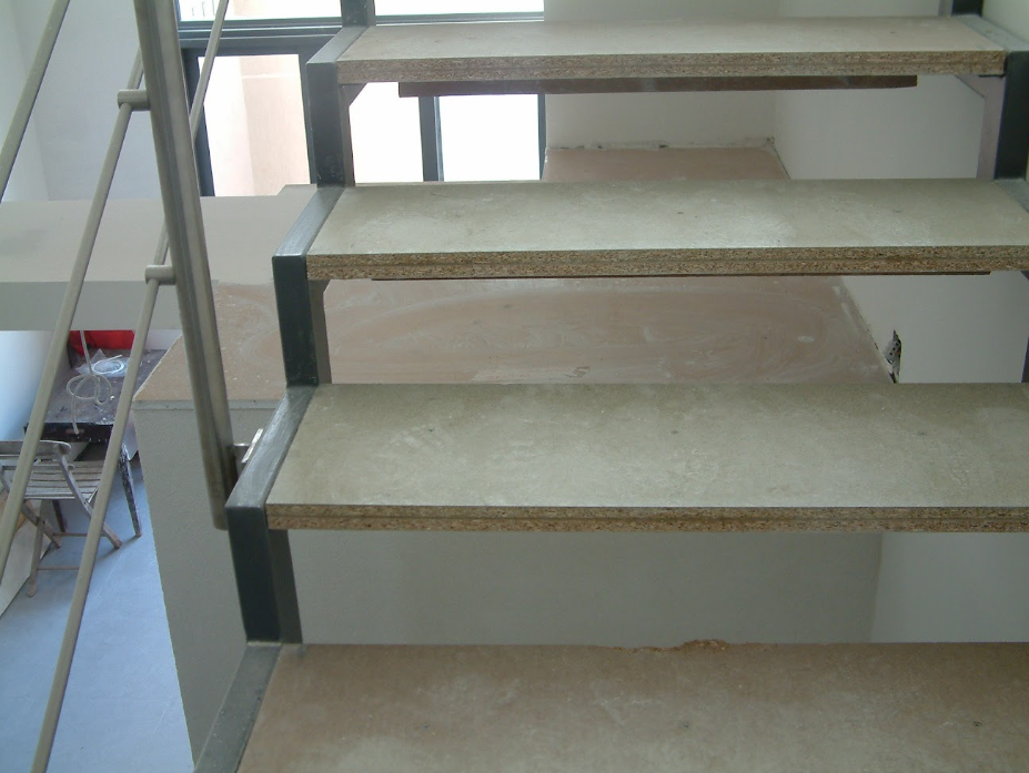 Interior view of unfinished concrete stairs with metal railing.