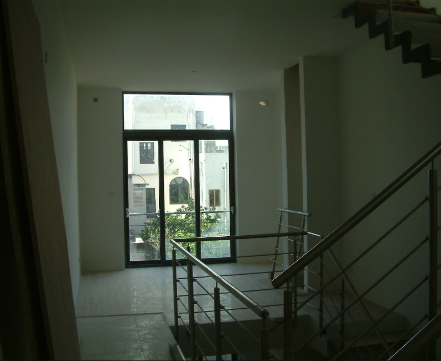 Empty room with large window and metal staircase.