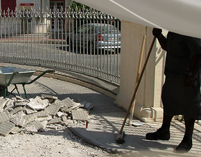 Person sweeping debris near a gated fence.