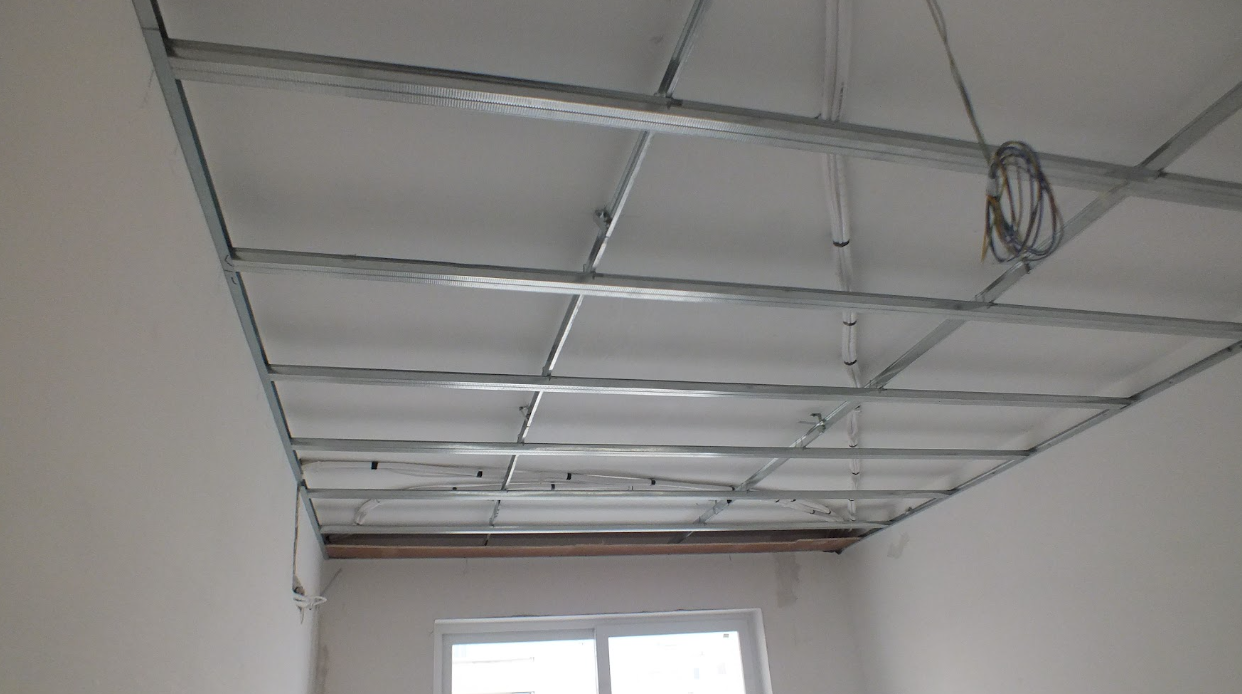 Ceiling under renovation with metal framing for drywall, wires hanging, and a window below.