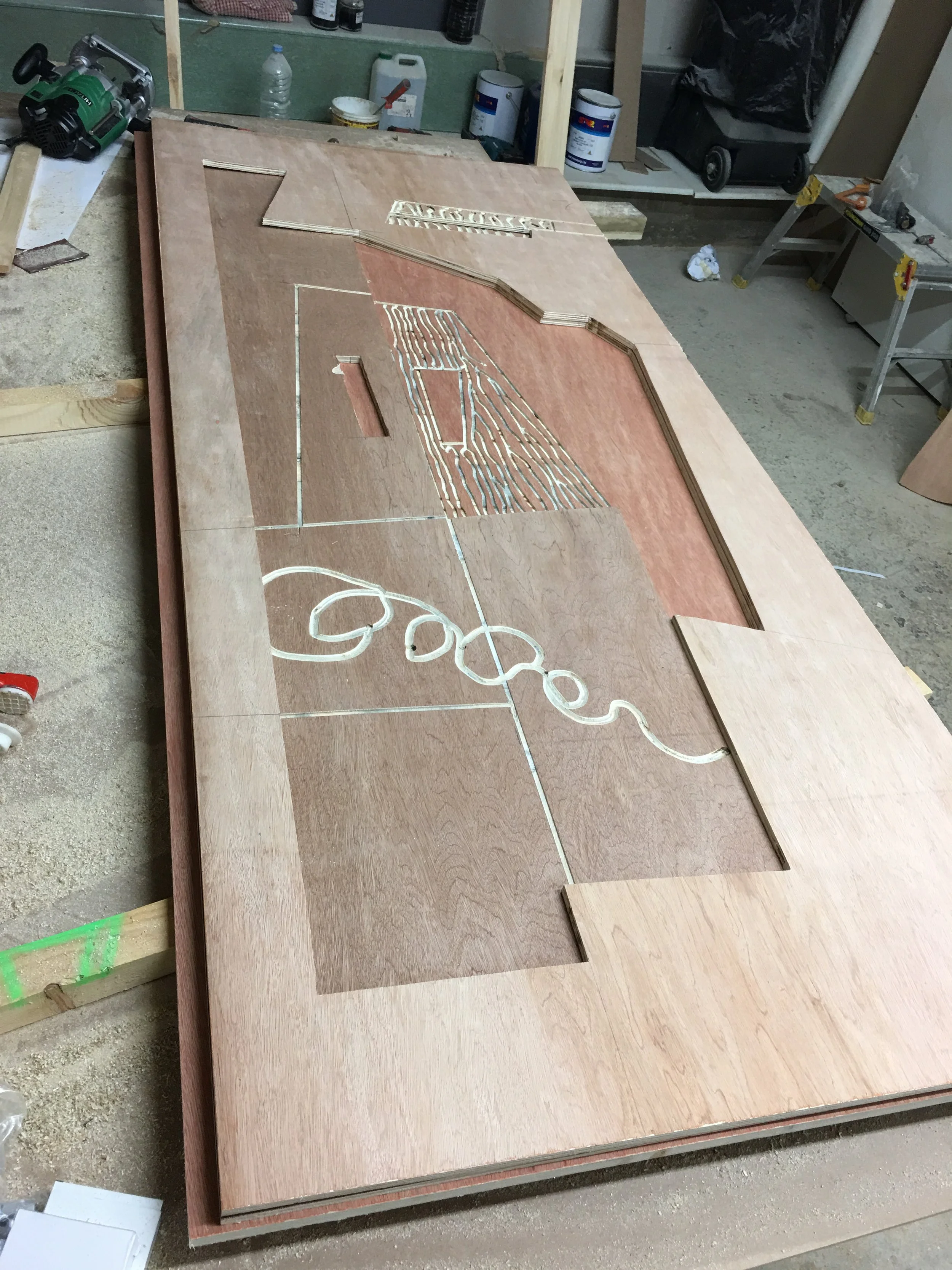 Wooden project table with cutout designs and tools in a workshop setting.