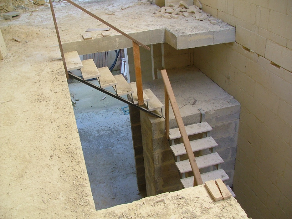 Construction site with incomplete concrete stairs and wooden handrails.