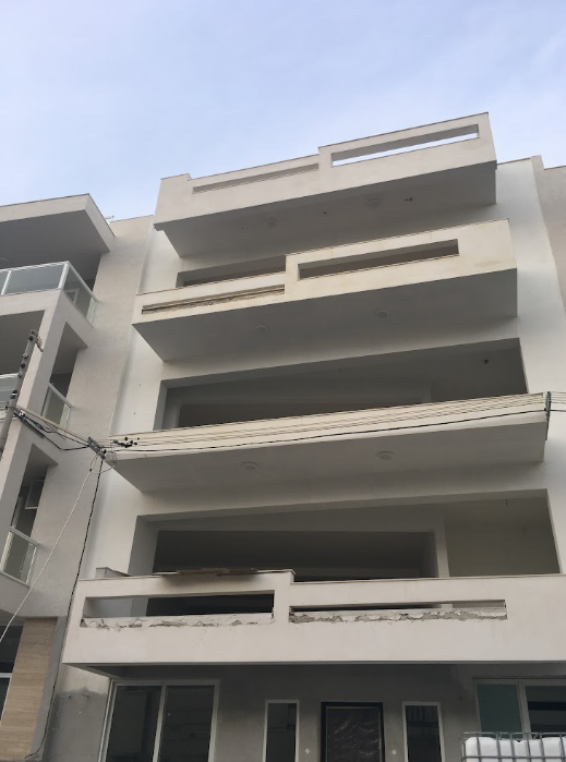 Front view of a modern multi-story white apartment building with balconies