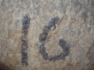 The letters 'I' and 'G' spelled out with dark stones on a rough, light-colored stone surface.