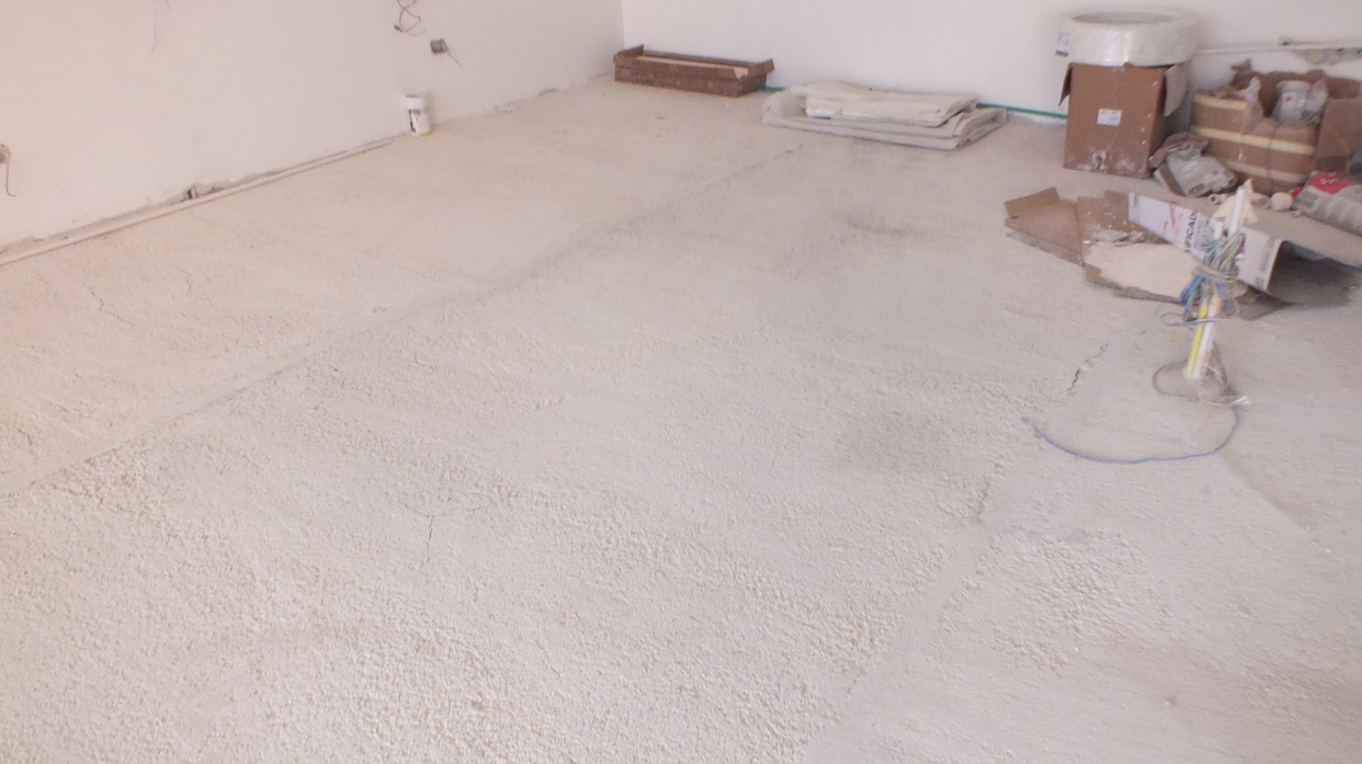 Room under construction with a rough concrete floor and construction supplies on the side.