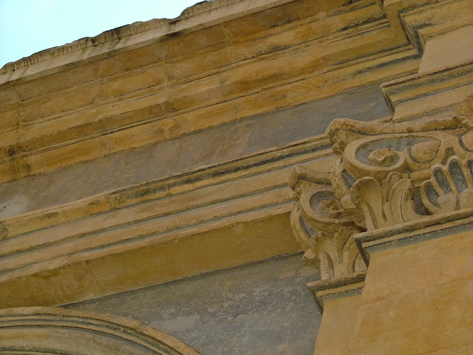 Close-up of a detailed stone architectural column with ornamental carvings on a historic building, with a beige color and layered design.