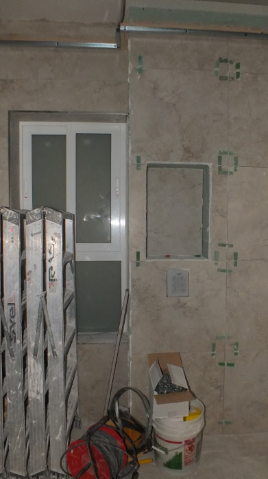 Construction site with a wall, window, ladder, and construction tools and materials.