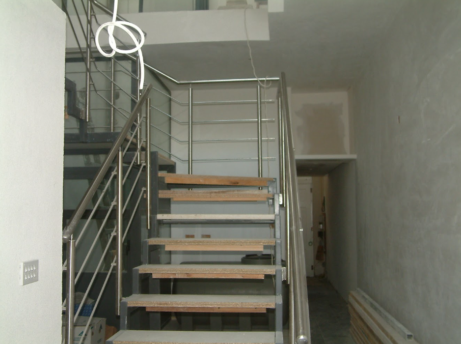 Interior view of a partially constructed staircase with metal railings and wooden steps.
