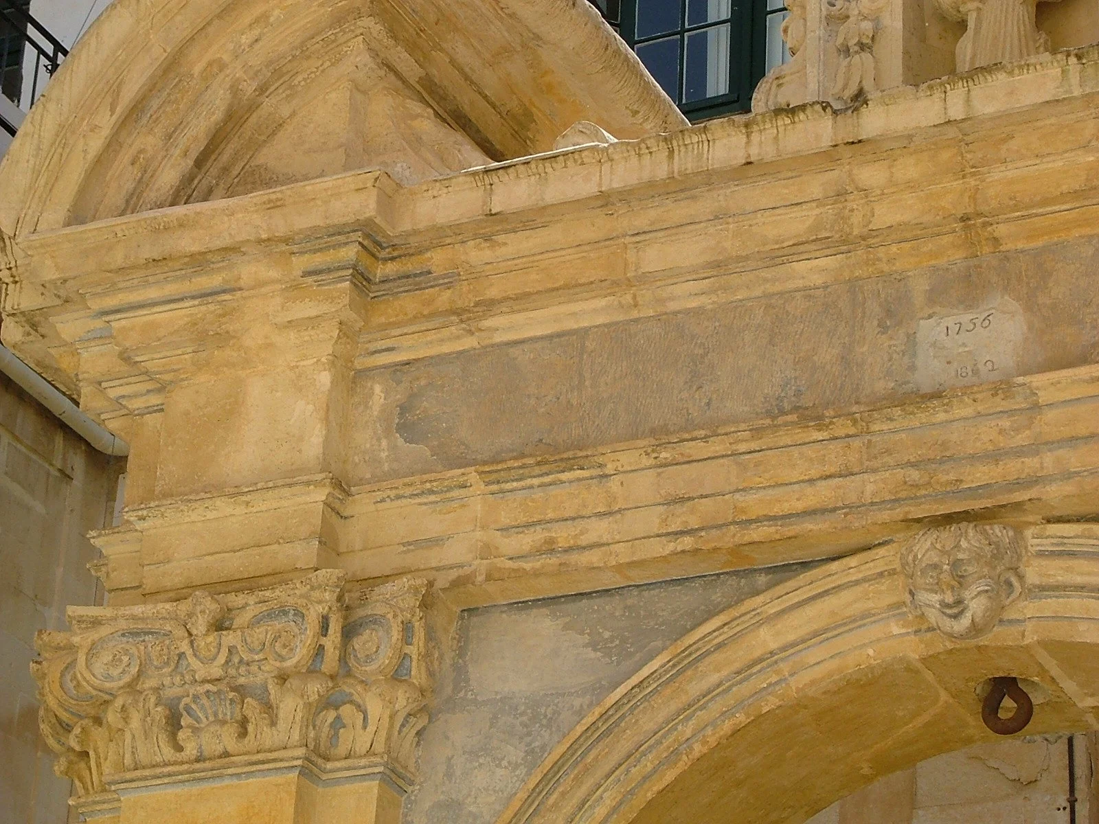 Close-up view of an ornate stone arch and architectural details on a historic building, with decorative carvings and inscriptions.