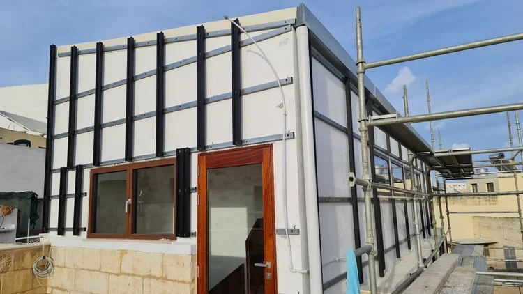 Exterior of a building under construction with scaffolding, a glass door, and framed windows.