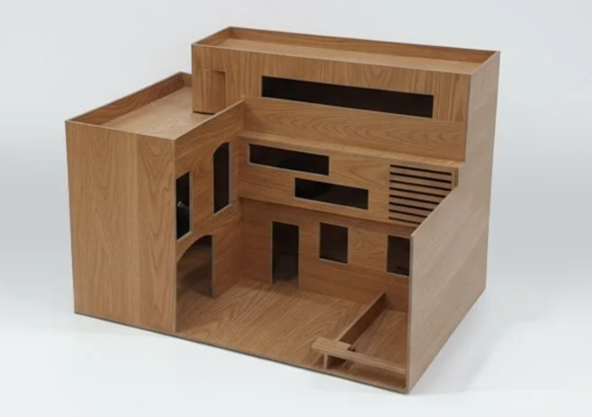 A wooden dollhouse with multiple rooms, windows, and various architectural features.