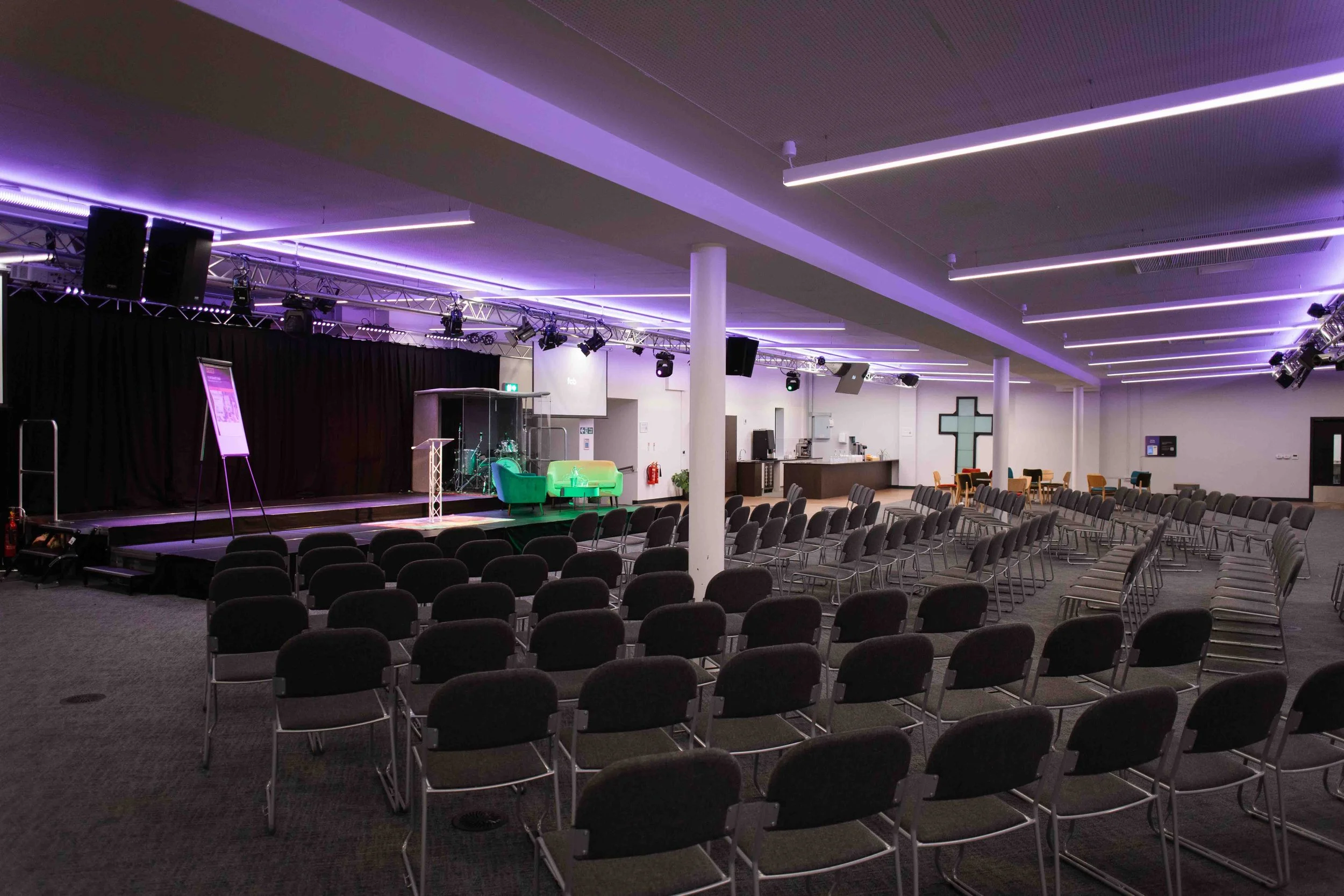 An event hall rental in Bradford with rows of chairs, a stage with musical instruments, and purple lighting accents.