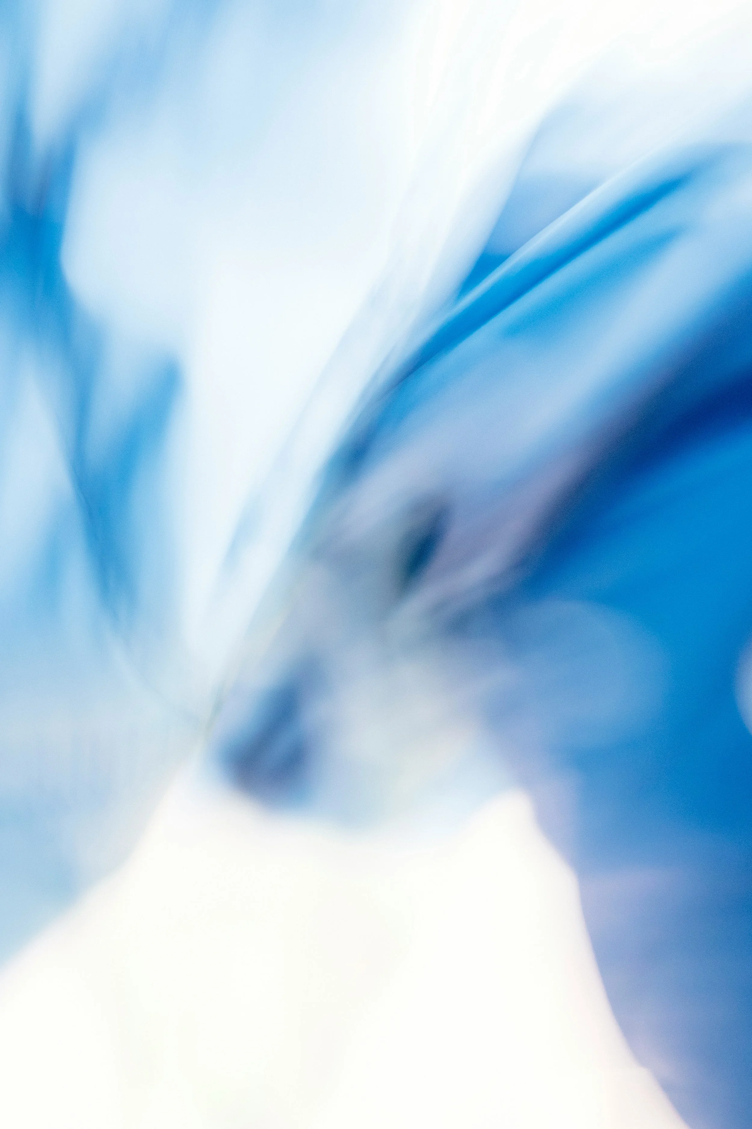 Scenic landscape of a lake surrounded by rolling hills and mountains under cloudy sky.