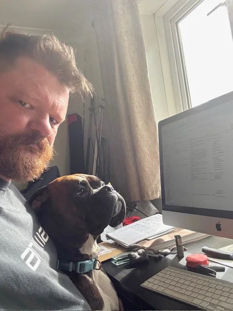 man and dog sitting at desktop computer