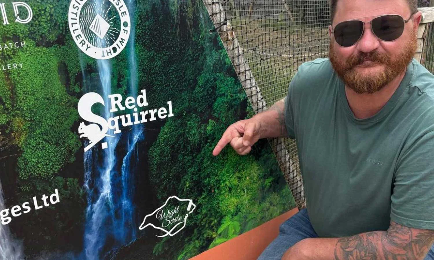 ian pointing at his logo on a promotional banner