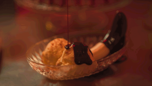 A banana ice cream in the shape of a penis is being drippedin chocolate