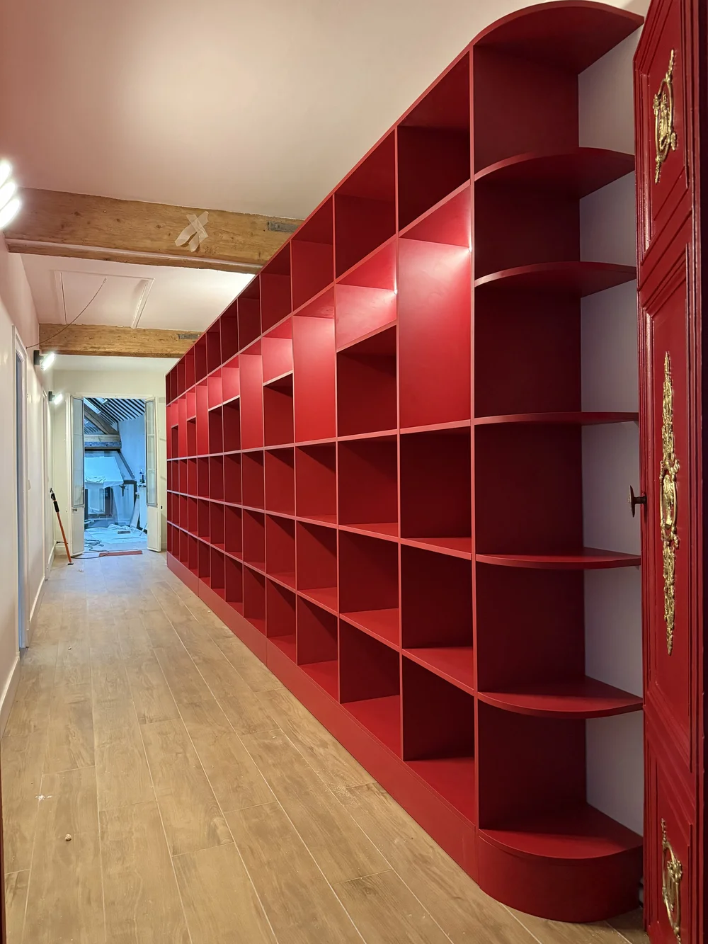 Bibliothèque rouge laquée sur-mesure occupant tout un mur de couloir