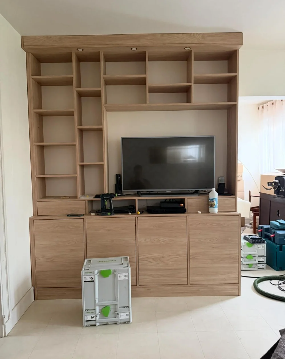 Meuble TV et bibliothèque sur-mesure en chêne clair avec niches et placards, photographié en fin de pose