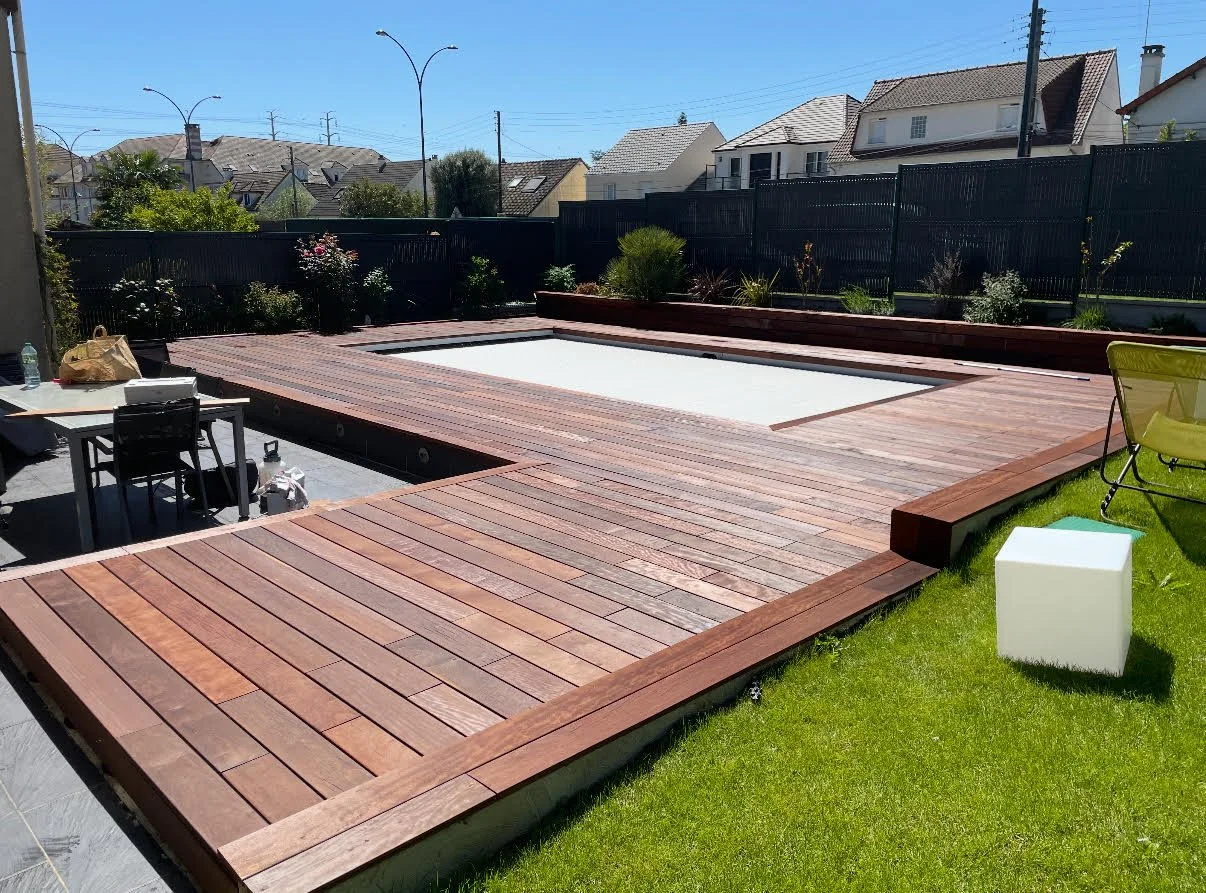 Terrasse en bois exotique construite autour d'une piscine dans un jardin