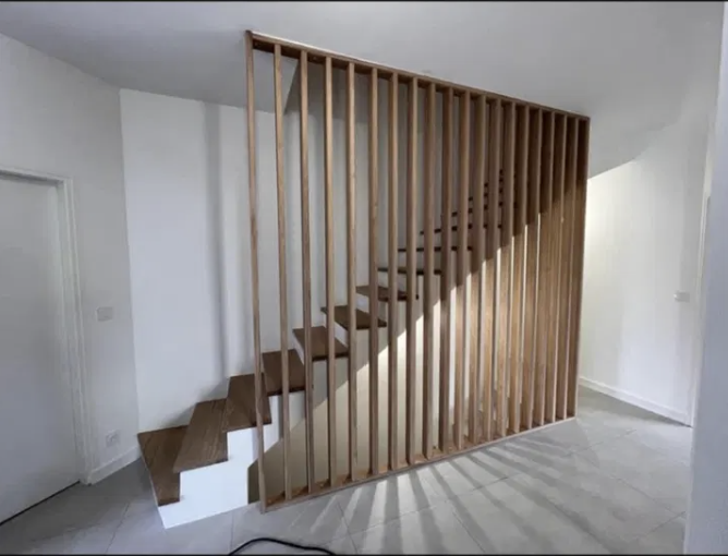Claustra en tasseaux de bois séparant l'escalier de la pièce de vie