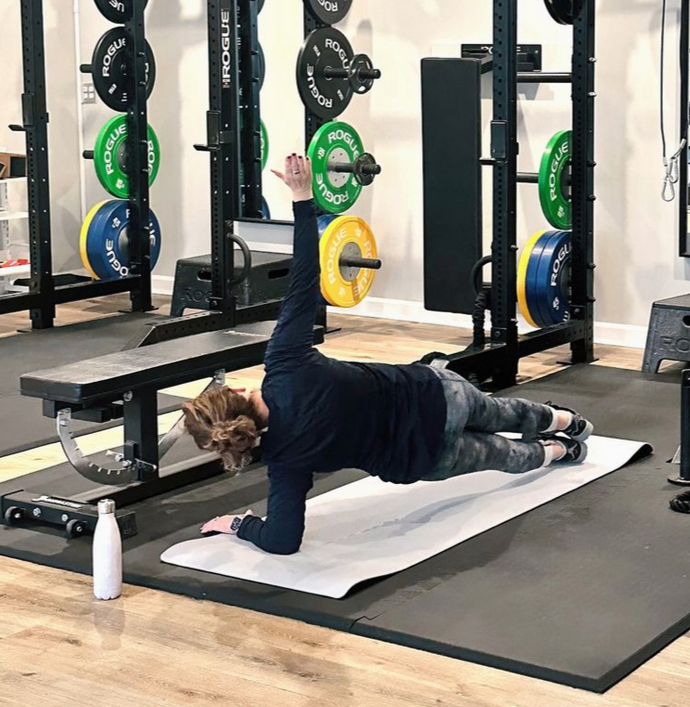 Three men in a gym lifting dumbbells, with weightlifting equipment in the background.