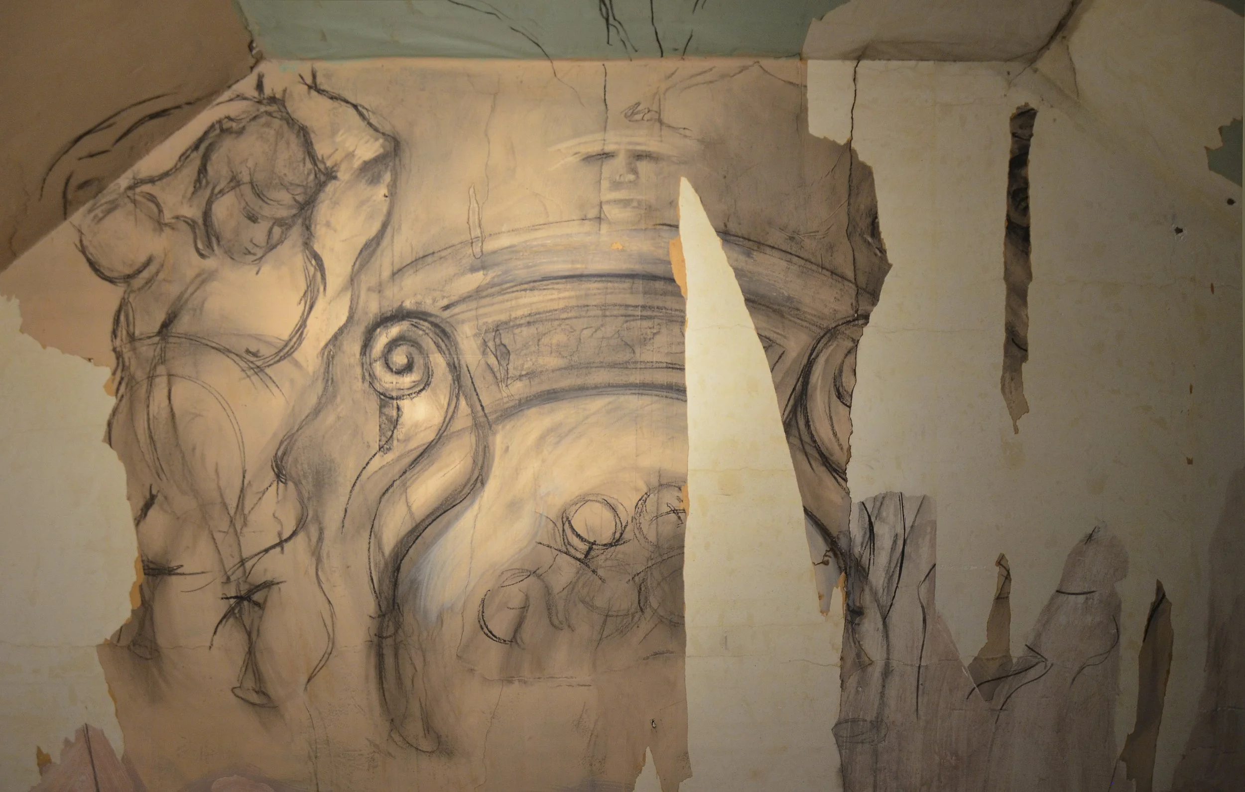 A detailed pencil sketch on a wall depicting a classical-style figure next to ornate architectural elements, partially covered by torn paper and peeling plaster.