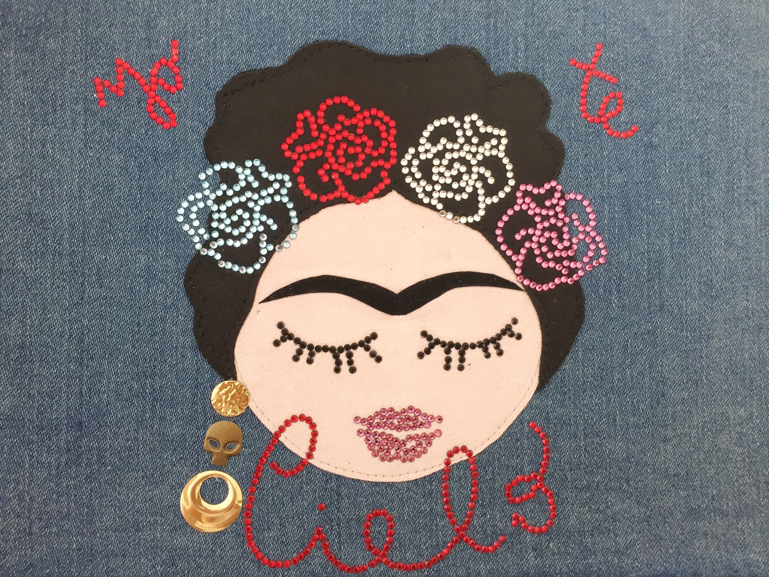 decorazione su denim con volto in stile Frida Kahlo composto da ritagli di pelle e impreziosito con strass swarovski e borchie