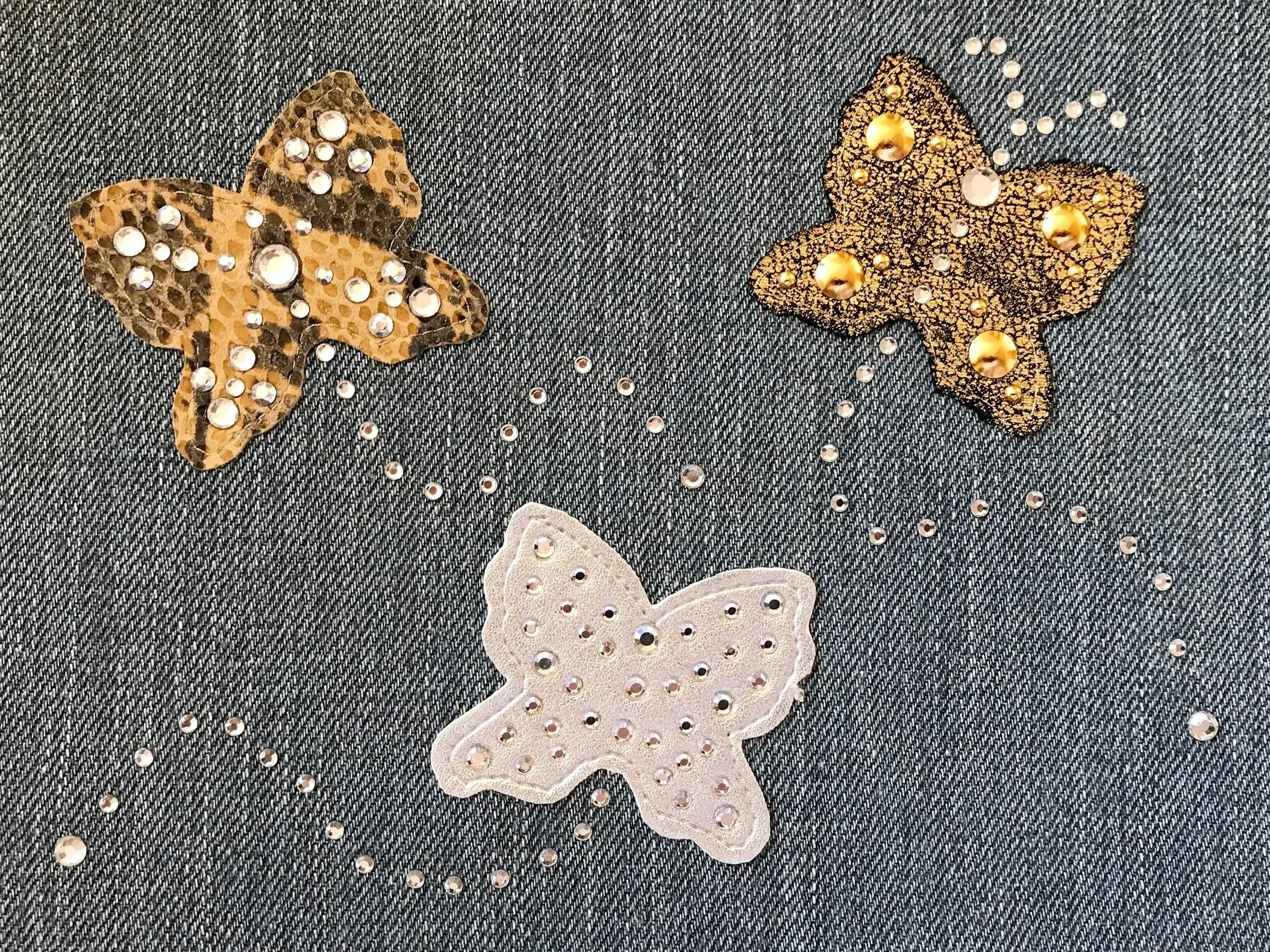Decorazioni realizzate con strass e borchie su denim, pelle e ecopelle