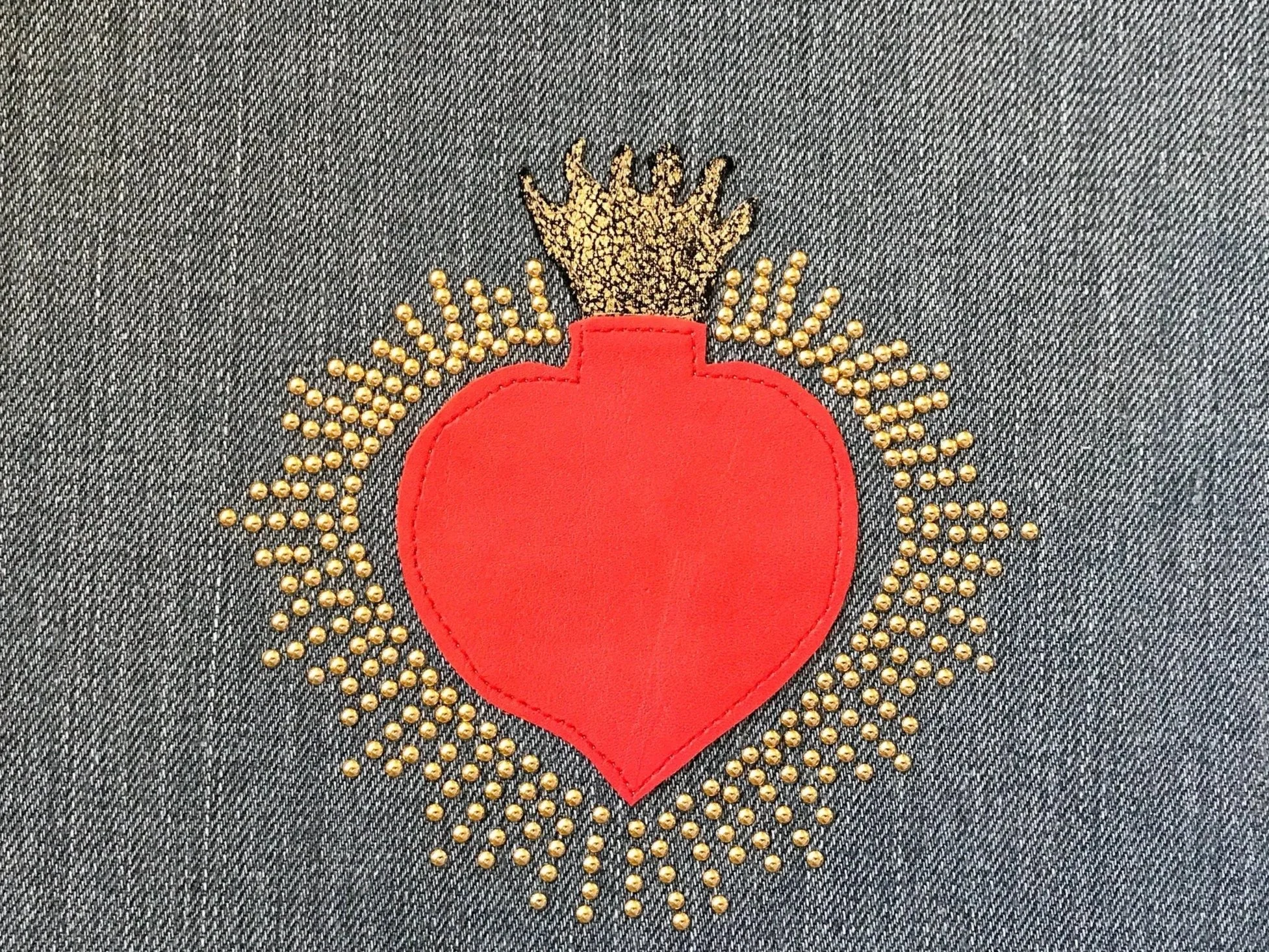 Cuore sacro realizzato con intarsi in pelle e raggiera realizzate con borchie termoadesive applicate su denim