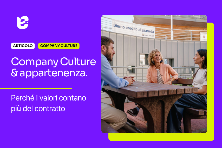 Tre persone che siedono a un tavolo di legno su un terrazzo, conversano sorridendo, con un edificio moderno sullo sfondo e un cartello con scritto 'Diamo credito al pianeta'.
