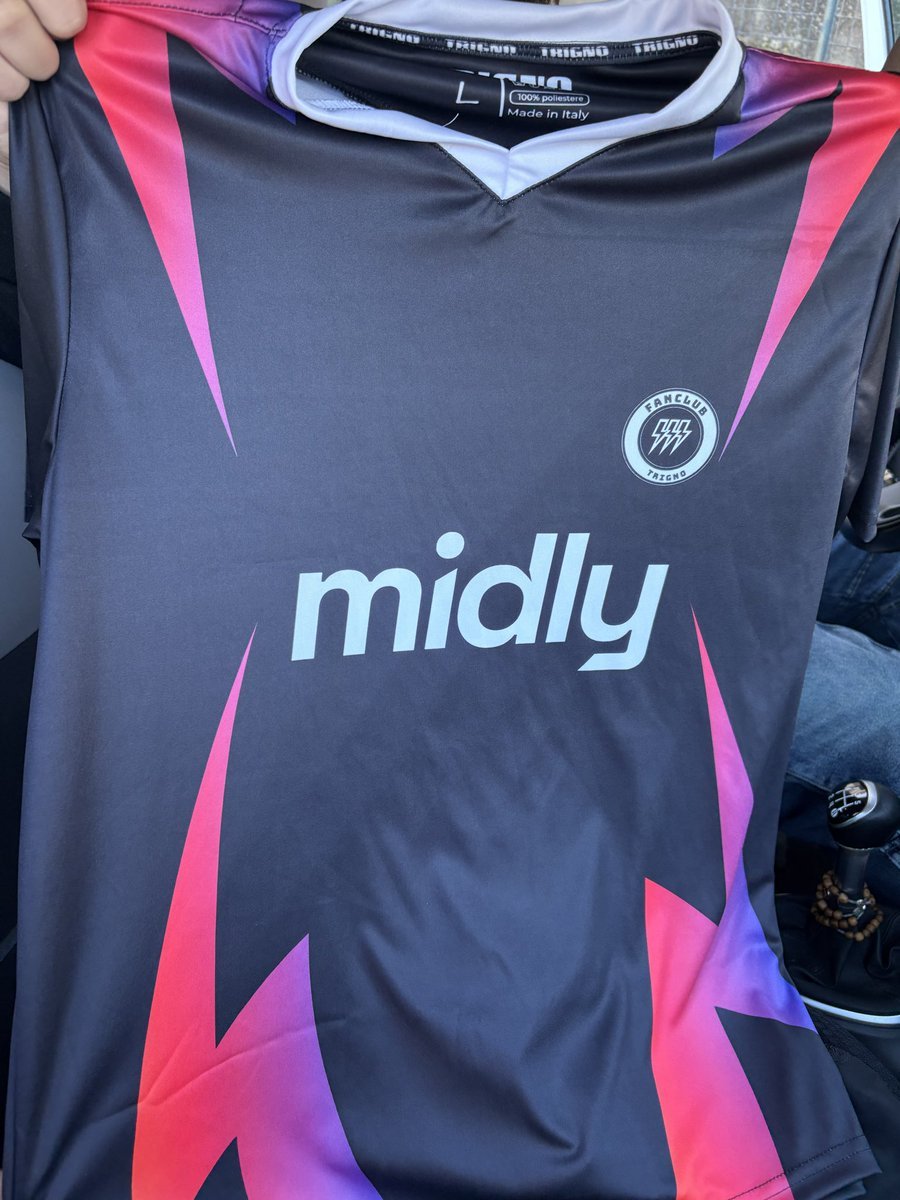 Maglia da calcio di colore nero con dettagli rosa e viola, con lo stemma del Fanclub Trigono e il logo 'midy' in centro.
