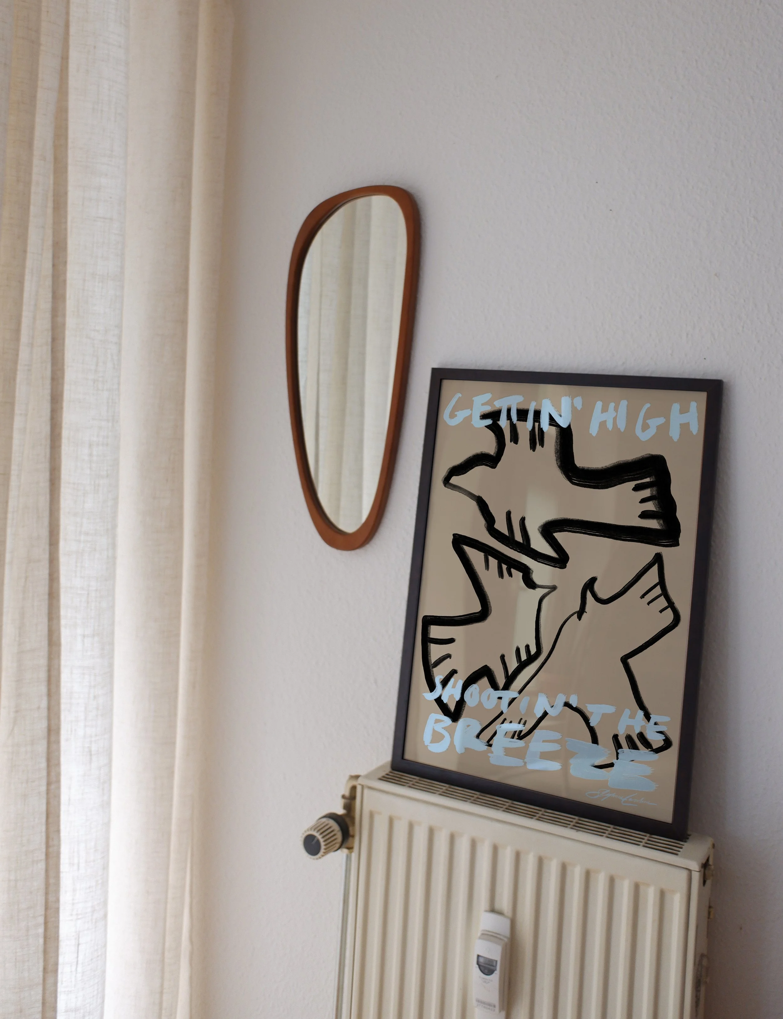 Minimalist typography poster featuring hand-drawn birds in black and beige with pastel blue lettering. poster in frame in a trendy bright living room next to abstract mirror and linen curtains