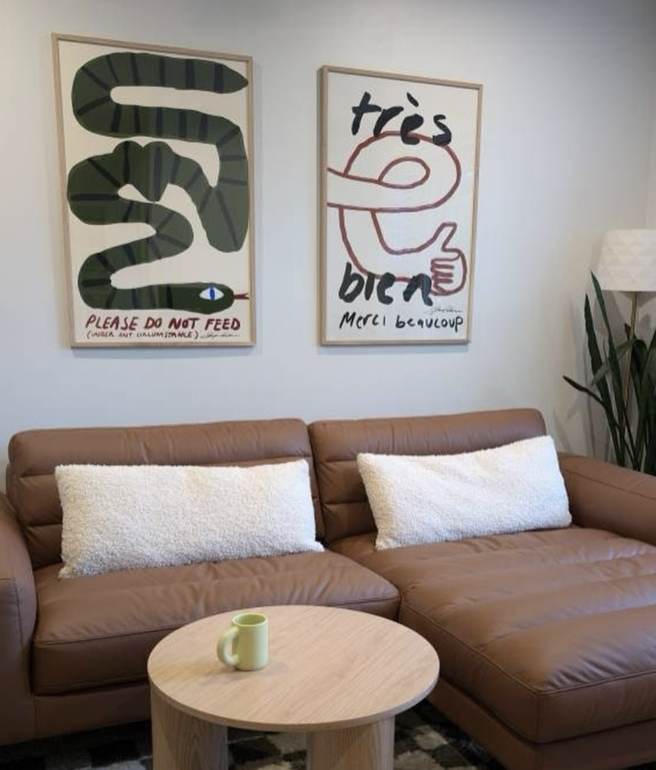 KunstbyStephie minimalistic art prints "Don't Feed the Snake" and "Tres Bien" hanging in a gallery wall above the couch in a trendy living room 