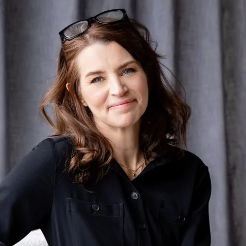 business woman wearing navy jacket with glasses on head
