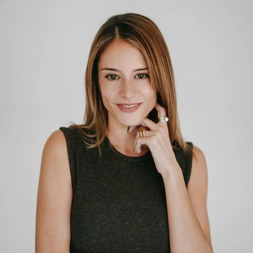 brunette woman smiling to camera against a grey backdrop